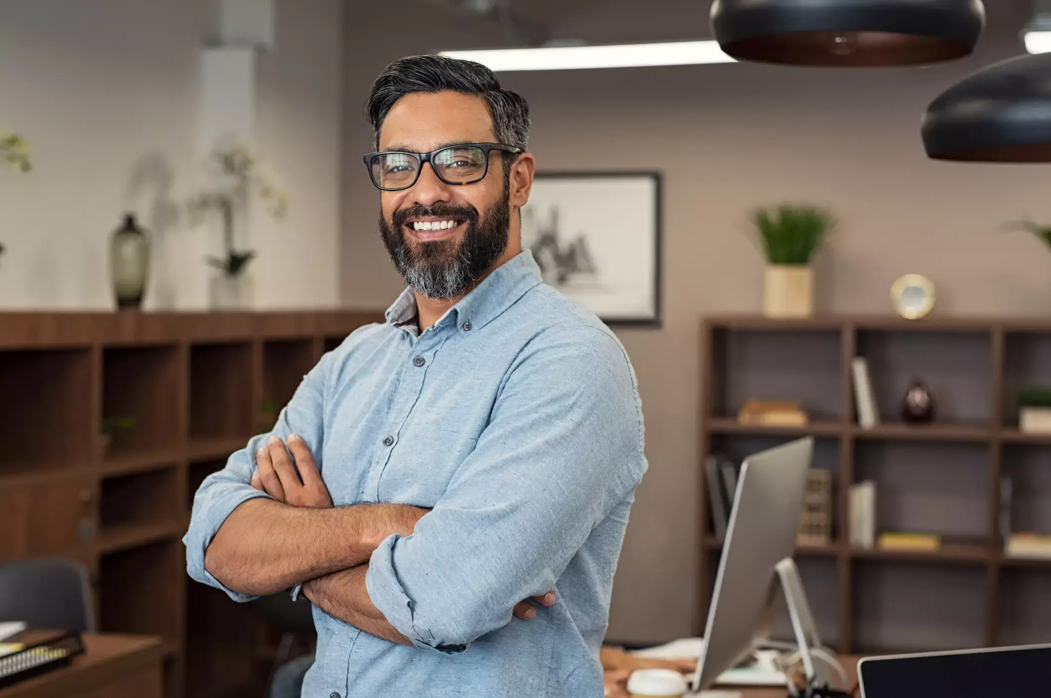 Smiling business owner with arms crossed in a modern office, conveying trust and professionalism for small business loans.